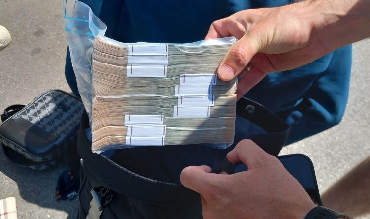 Horgászkalapos férfi hátizsákkal az utcán, budapesti csalási ügy gyanúsítottja