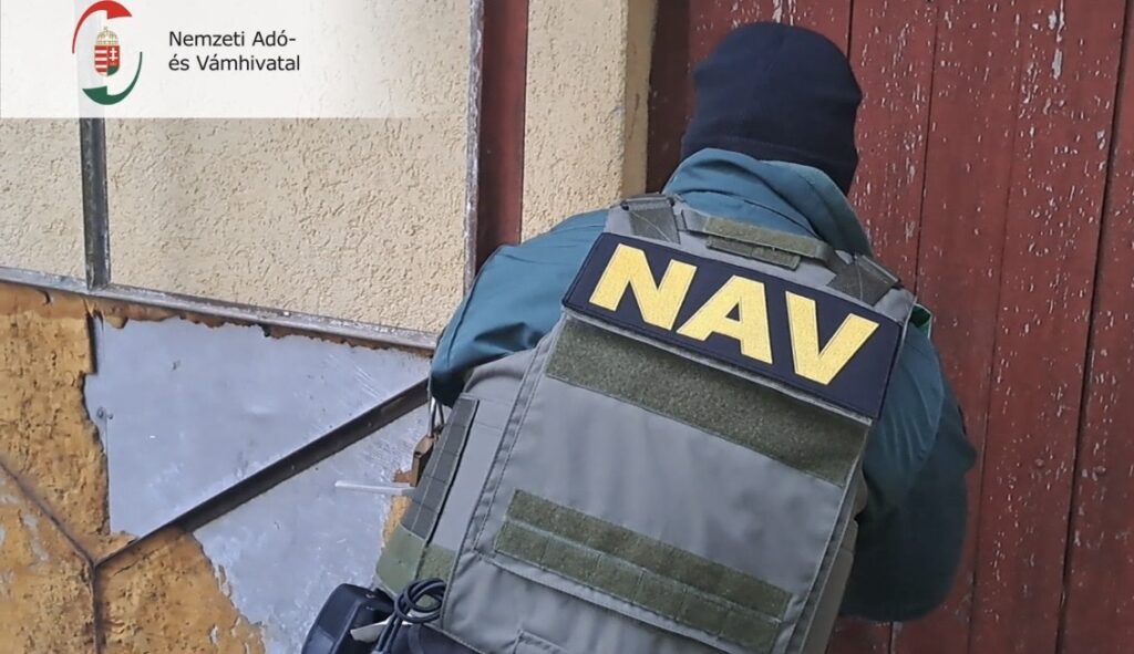 NAV-mellényt viselő pénzügyőr egy nyírségi ház bejáratánál, ellenőrzés közben.