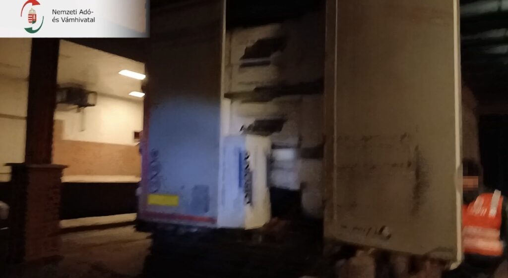 A teherautó kinyitott oldalfala, mellette NAV egyenruhás munkatárs, a raktér belseje félig látható