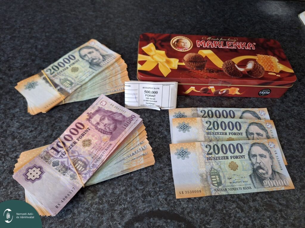 Lefoglalt készpénz kötegek és édességdoboz az asztalon, NAV-felvétel