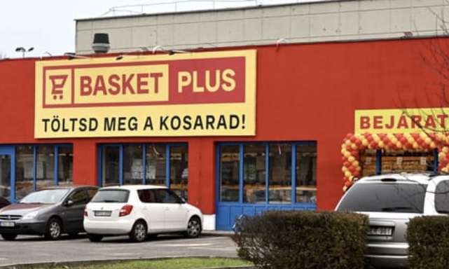 A Basket Plus piros homlokzatú áruháza a parkolóval.