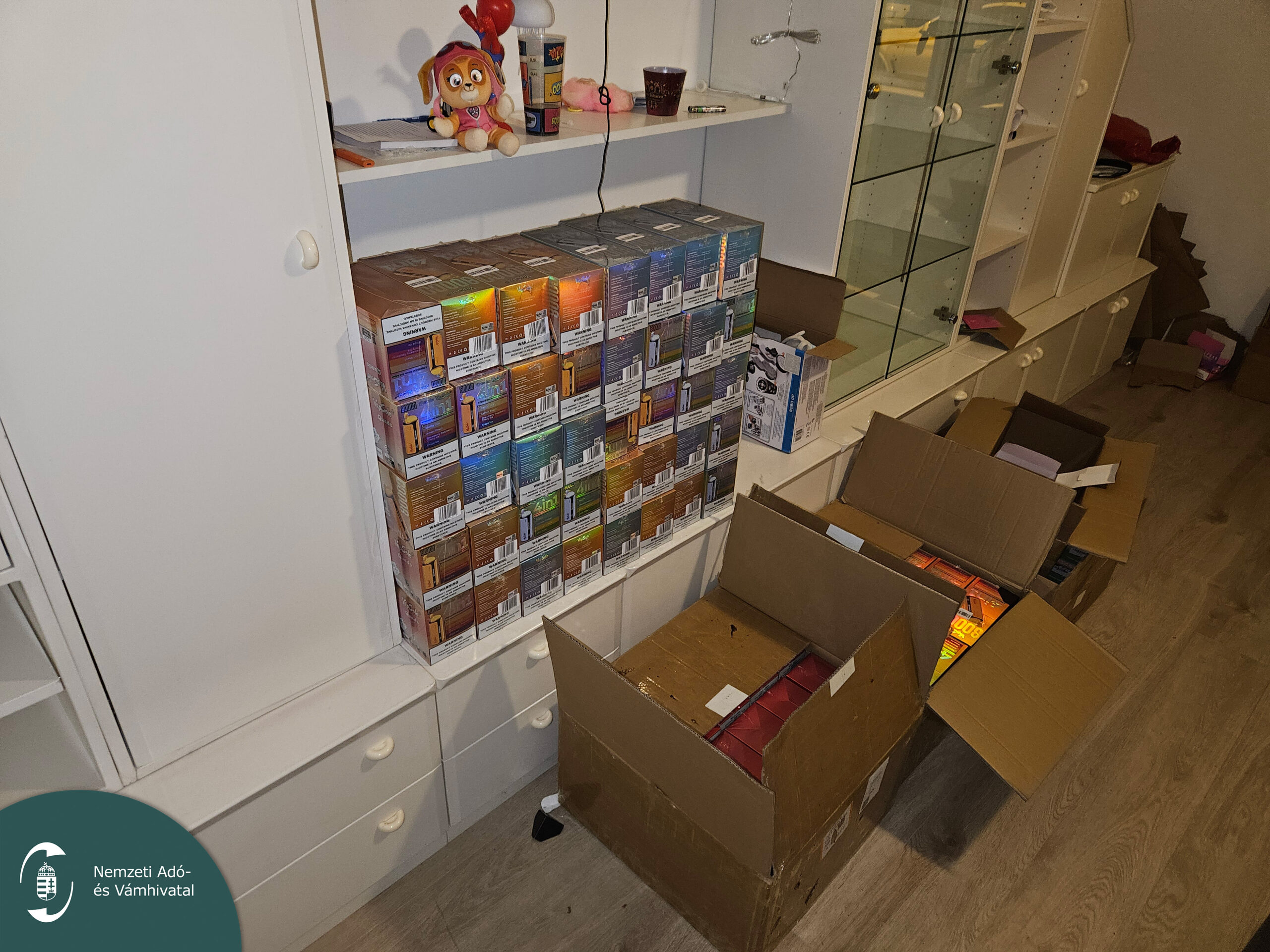 Illegális elektromos cigaretták dobozai egy lakás polcán és a padlón kartondobozokban