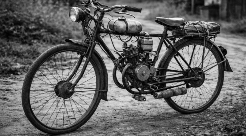 Házilag motorral felszerelt régi kerékpár közelről, poros falusi úton, ember nélkül.