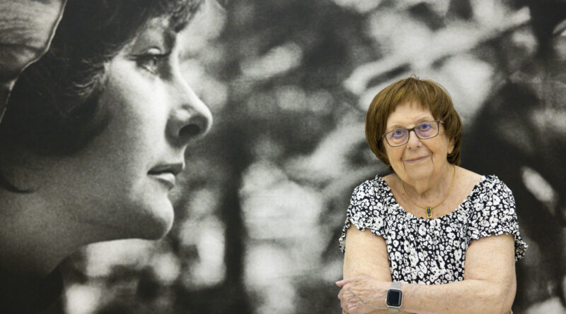 Keleti Éva portréja egy nagyméretű fekete fehér fotó előtt a Művészetek Házában