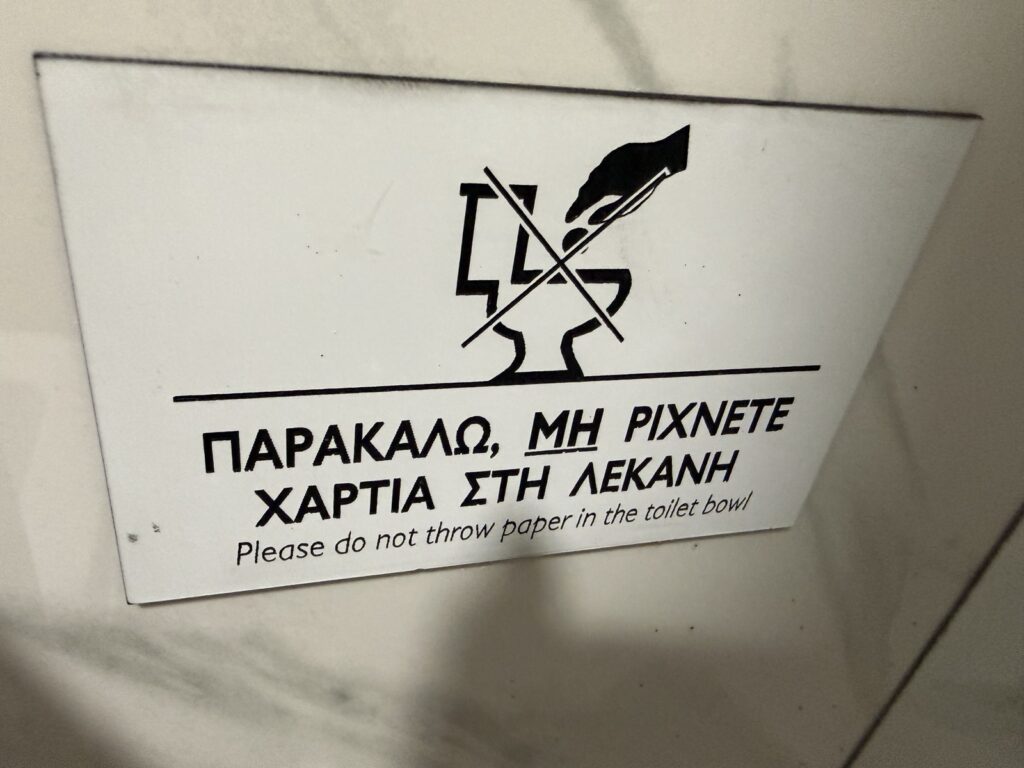 Görögországi figyelmeztető tábla, amely kéri a turistákat, hogy ne dobjanak papírt a WC-be