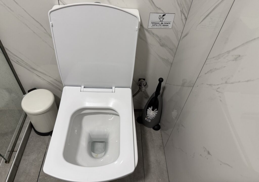 Modern mosdó Görögországban a papírhasználatra figyelmeztető táblával