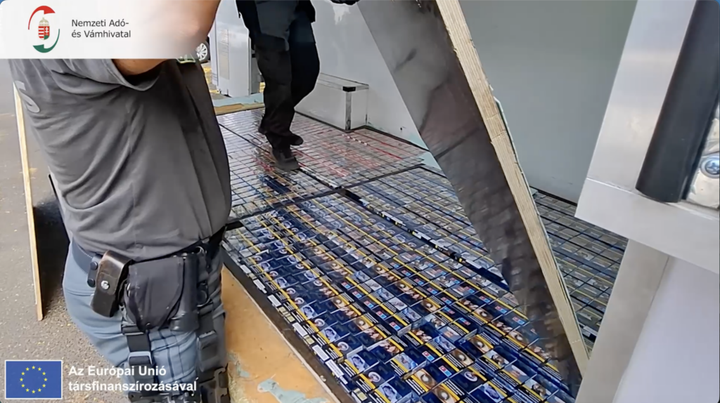 Több ezer doboz bolgár zárjegyes cigaretta látható a furgon padlója alatti titkos rekeszben.