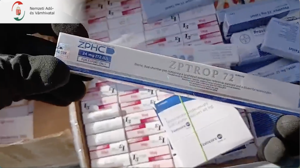 Nagy mennyiségű gyógyszeres doboz között egy hormonkészítményt mutat be a NAV pénzügyőre.