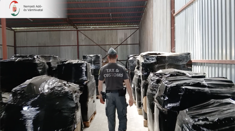A NAV pénzügyőre egy fóliába csomagolt raklapokkal teli budapesti raktárban, ahol több mint 18 ezer illegális elektronikus cigarettát találtak.