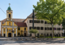 Semmelweis Szent Rókus Egészségközpont épülete nyári időben, zöld lombos fákkal és napsütéses környezetben.
