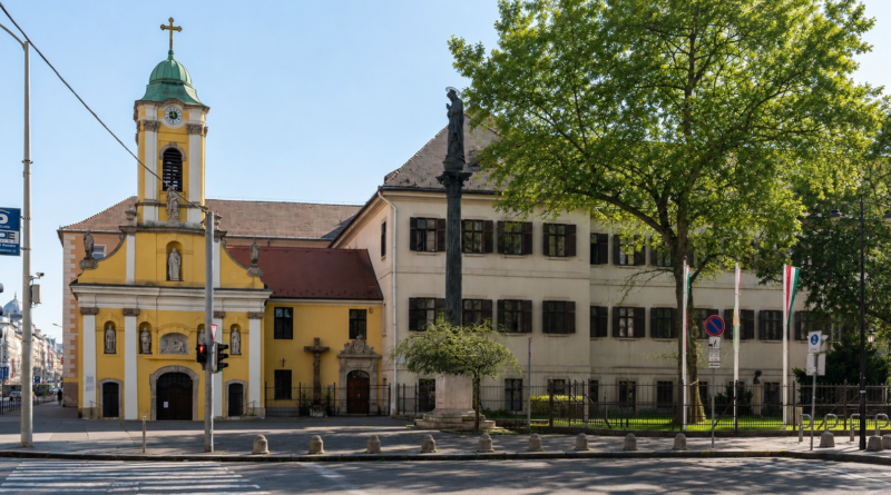 Semmelweis Szent Rókus Egészségközpont épülete nyári időben, zöld lombos fákkal és napsütéses környezetben.