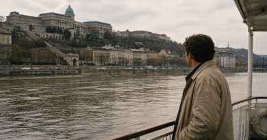 Férfi egy dunai városnéző hajóról nézi Budapest budai oldalát