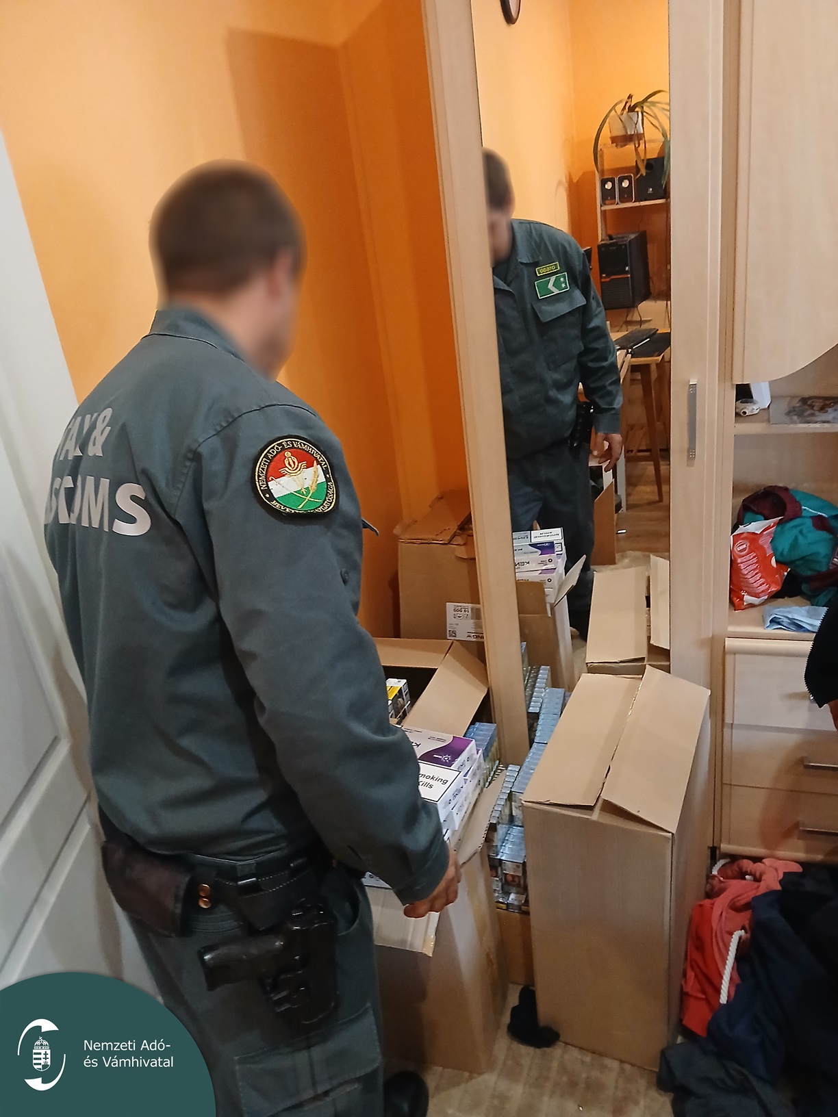 NAV-pénzügyőr vizsgálja a családi házban felhalmozott cigarettás dobozokat